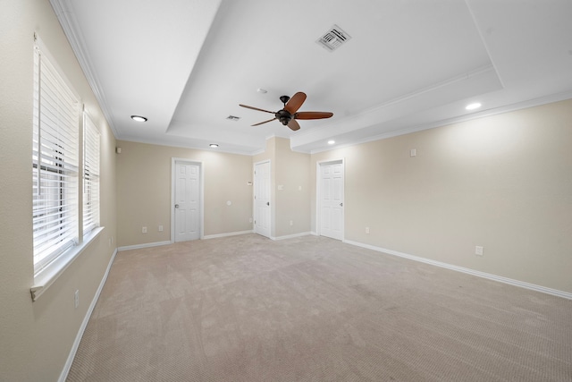 empty room featuring crown molding, light colored carpet, ceiling fan, and a tray ceiling