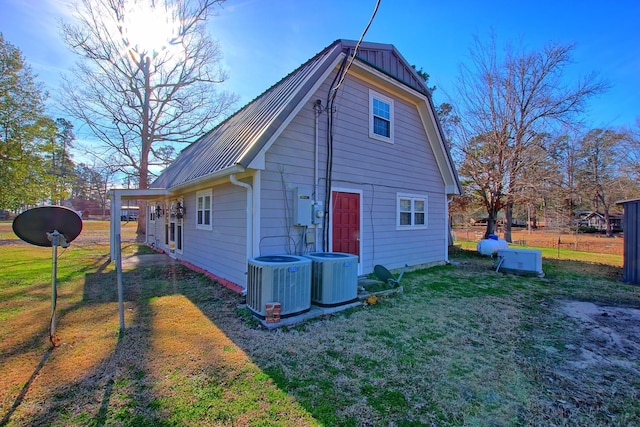 rear view of property featuring central AC unit and a lawn