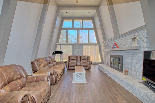 living room with a towering ceiling, a fireplace, a healthy amount of sunlight, and hardwood / wood-style flooring