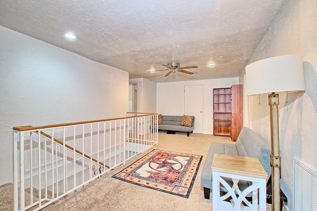 interior space featuring ceiling fan, light colored carpet, and a textured ceiling