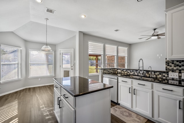 kitchen with sink, white cabinetry, tasteful backsplash, stainless steel dishwasher, and dark stone counters