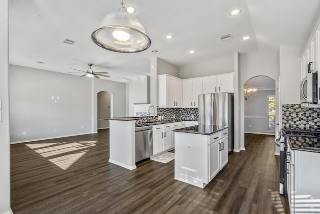 kitchen with appliances with stainless steel finishes, white cabinets, backsplash, hanging light fixtures, and a center island