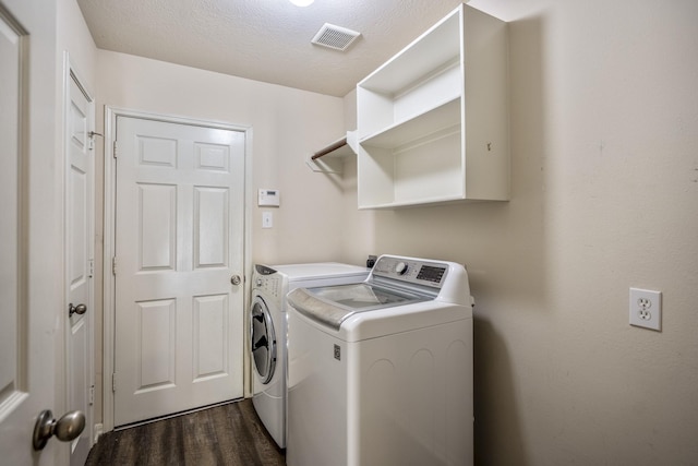 laundry room with dark wood-type flooring, washing machine and dryer, and a textured ceiling