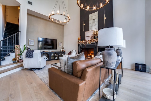 living room with a high ceiling, a chandelier, and light hardwood / wood-style floors