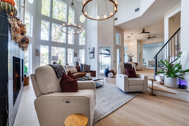 living room with plenty of natural light, a towering ceiling, a chandelier, and light hardwood / wood-style floors