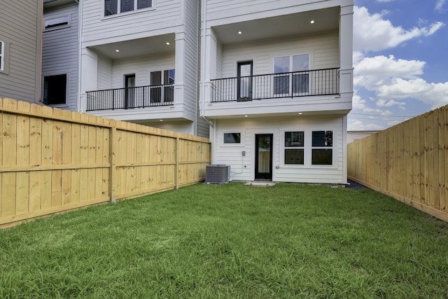 rear view of property featuring a lawn and central air condition unit