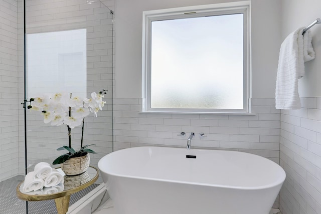 bathroom featuring a bath and tile walls