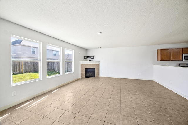 unfurnished living room with a tiled fireplace and light tile patterned flooring