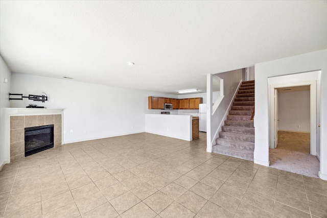 unfurnished living room with light tile patterned flooring and a tiled fireplace