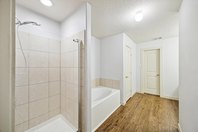 bathroom featuring hardwood / wood-style floors, shower with separate bathtub, and a textured ceiling