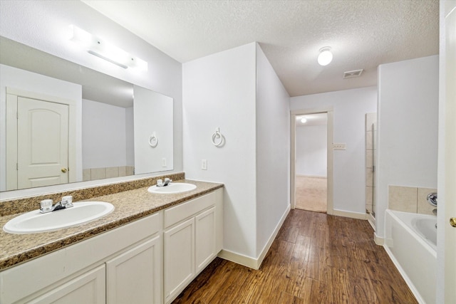 bathroom featuring vanity, hardwood / wood-style floors, a bathtub, and a textured ceiling