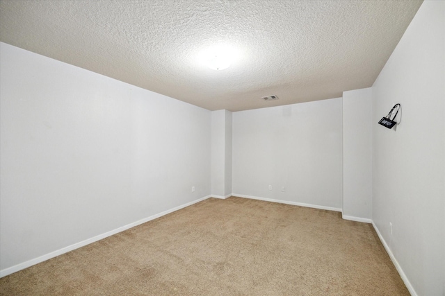 spare room featuring light colored carpet and a textured ceiling