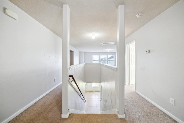 stairs with a textured ceiling and carpet