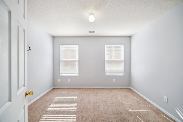 carpeted empty room with a textured ceiling