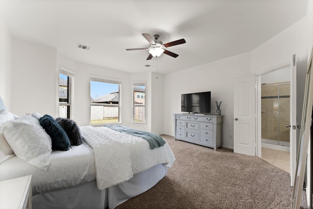 bedroom featuring light carpet, connected bathroom, and ceiling fan