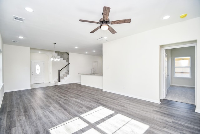 unfurnished living room featuring wood-type flooring, sink, and ceiling fan with notable chandelier