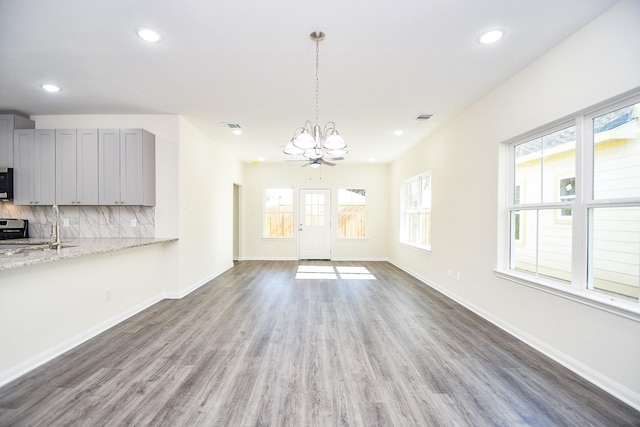 unfurnished living room featuring sink, a healthy amount of sunlight, hardwood / wood-style floors, and a notable chandelier