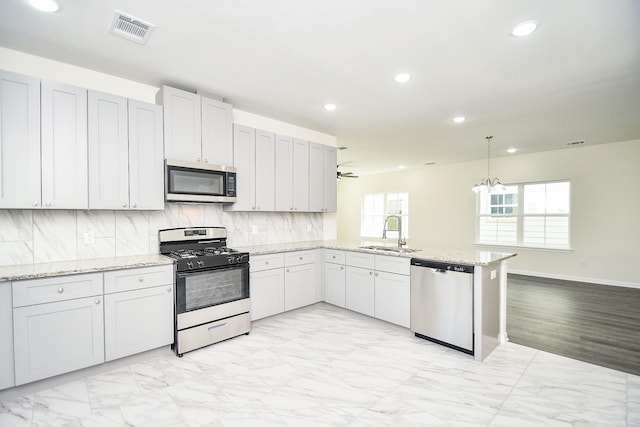 kitchen featuring appliances with stainless steel finishes, pendant lighting, white cabinetry, sink, and kitchen peninsula