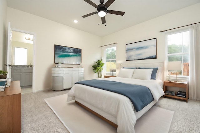 carpeted bedroom with multiple windows, connected bathroom, sink, and ceiling fan