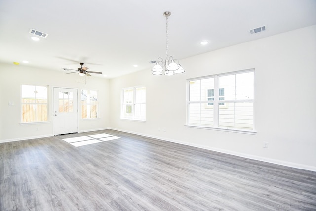 empty room with ceiling fan with notable chandelier and dark hardwood / wood-style flooring