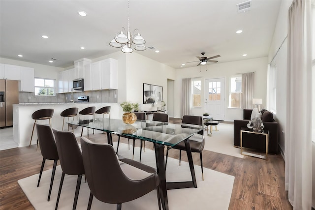 dining room with ceiling fan with notable chandelier and dark hardwood / wood-style floors