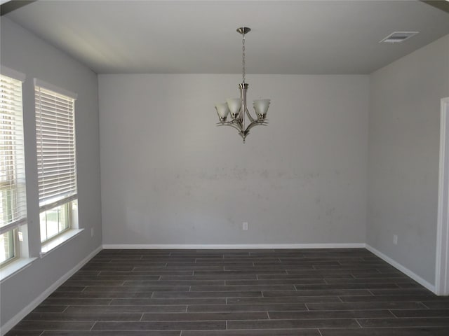 spare room featuring dark hardwood / wood-style flooring and a notable chandelier