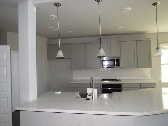 kitchen featuring light stone counters, backsplash, hanging light fixtures, and appliances with stainless steel finishes