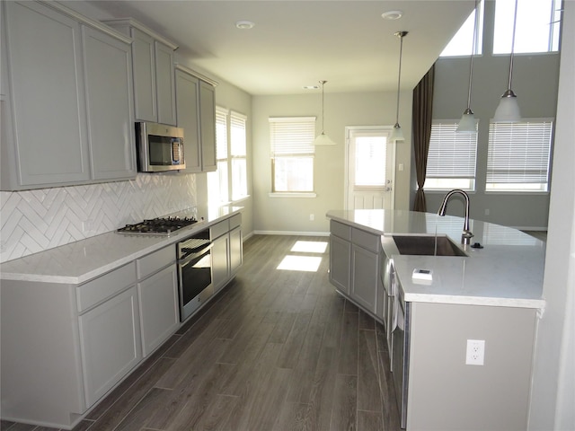 kitchen with decorative light fixtures, sink, gray cabinetry, backsplash, and stainless steel appliances