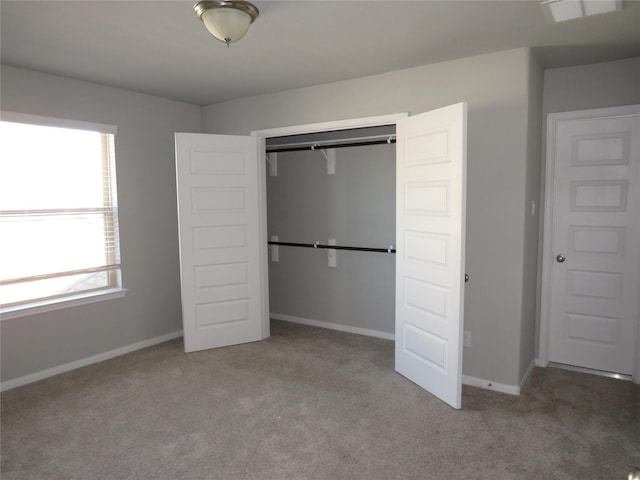 unfurnished bedroom with multiple windows, light colored carpet, and a closet