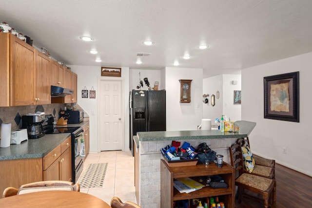 kitchen featuring light tile patterned flooring, backsplash, and black appliances