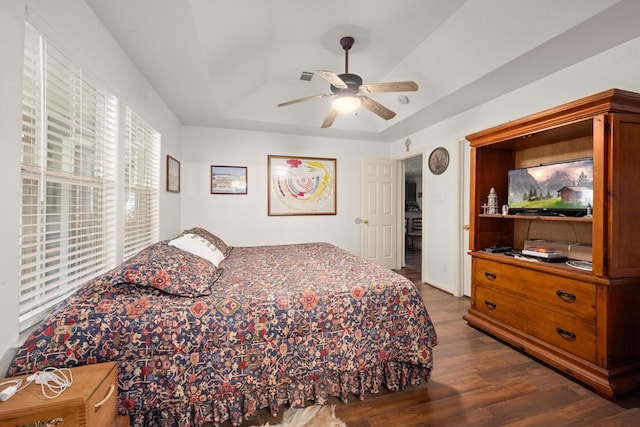 bedroom featuring dark hardwood / wood-style floors, ceiling fan, and a tray ceiling