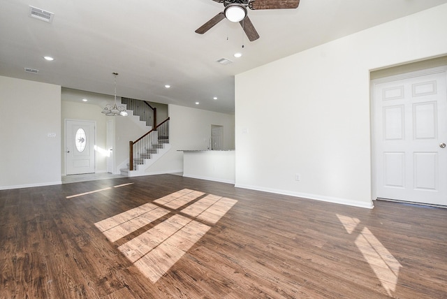 unfurnished living room featuring dark hardwood / wood-style floors and ceiling fan with notable chandelier