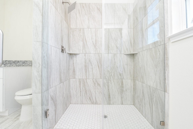 bathroom featuring a shower with door and toilet