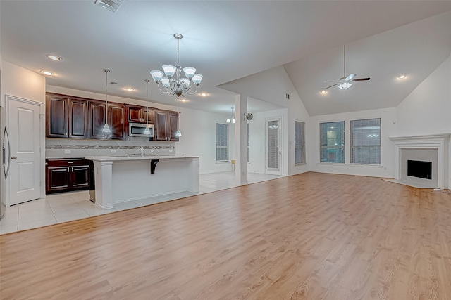 kitchen with pendant lighting, a breakfast bar, backsplash, a center island, and light wood-type flooring