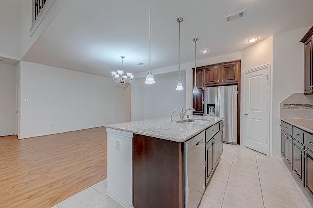 kitchen featuring sink, decorative light fixtures, light tile patterned floors, an island with sink, and stainless steel appliances