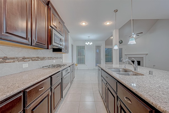 kitchen featuring appliances with stainless steel finishes, sink, hanging light fixtures, dark brown cabinetry, and light stone countertops