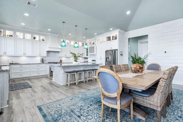 dining room featuring vaulted ceiling and light hardwood / wood-style floors