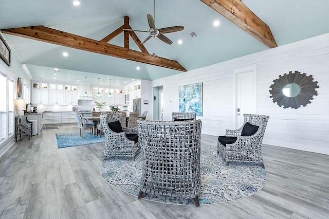 living room featuring beam ceiling, ceiling fan, high vaulted ceiling, and light wood-type flooring