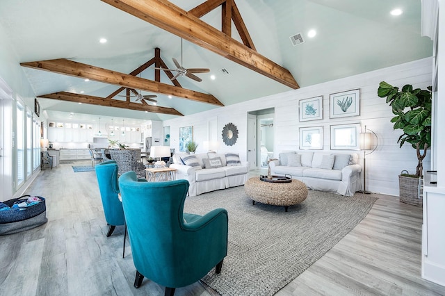 living room with high vaulted ceiling, beam ceiling, light hardwood / wood-style floors, and ceiling fan