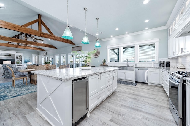 kitchen with pendant lighting, sink, appliances with stainless steel finishes, white cabinets, and a kitchen island