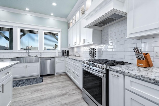 kitchen featuring white cabinetry, sink, stainless steel appliances, and custom range hood