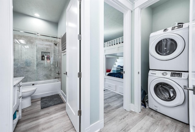 laundry room featuring light hardwood / wood-style floors and stacked washing maching and dryer