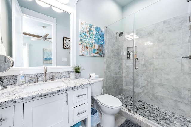 bathroom featuring ceiling fan, vanity, toilet, and a shower with door