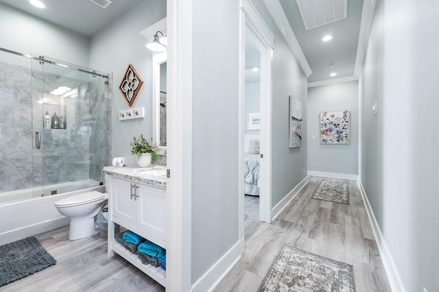 full bathroom with vanity, hardwood / wood-style floors, bath / shower combo with glass door, and toilet