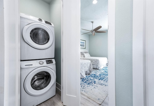 laundry room with stacked washer and dryer, ceiling fan, and light wood-type flooring