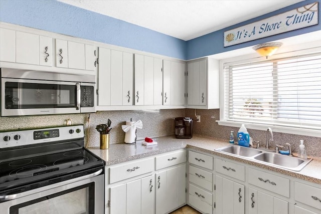 kitchen with tasteful backsplash, white cabinetry, appliances with stainless steel finishes, and sink