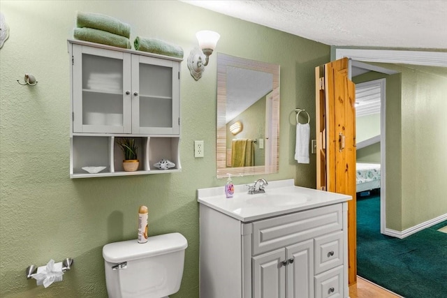 bathroom with vanity, toilet, and a textured ceiling