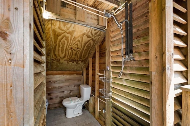 bathroom with hardwood / wood-style flooring, toilet, and wood walls