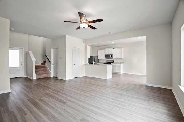 unfurnished living room featuring ceiling fan and light hardwood / wood-style flooring