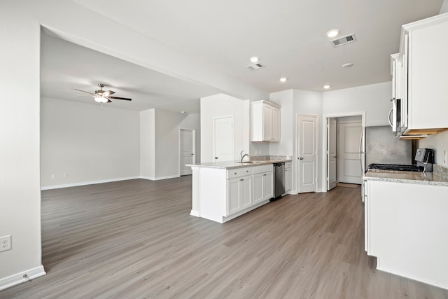 kitchen featuring light hardwood / wood-style flooring, ceiling fan, stainless steel appliances, light stone countertops, and white cabinets